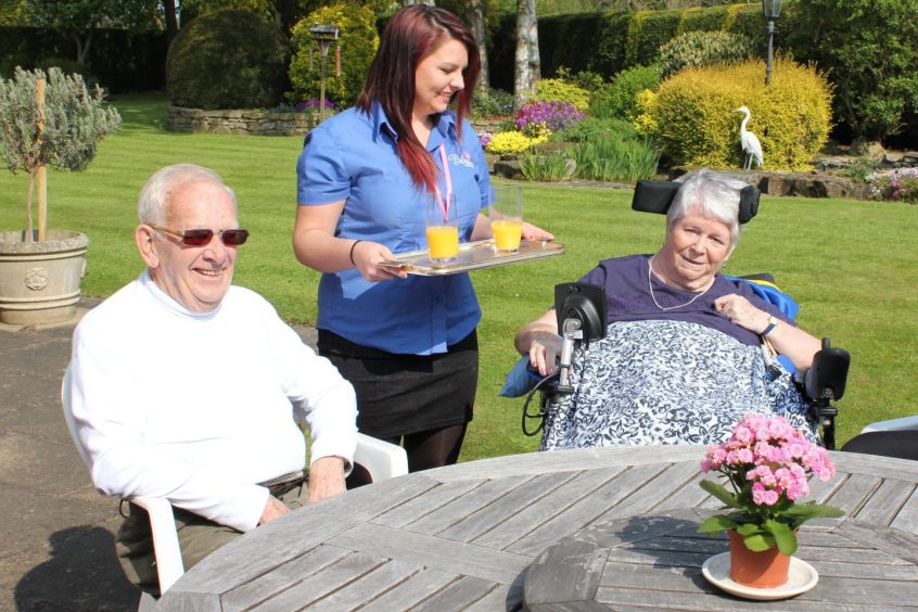 A blossom home carer carer with service users in the garden 