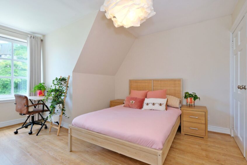 One of the bedrooms in the Ferryhill home with light wood tones and pink bedding
