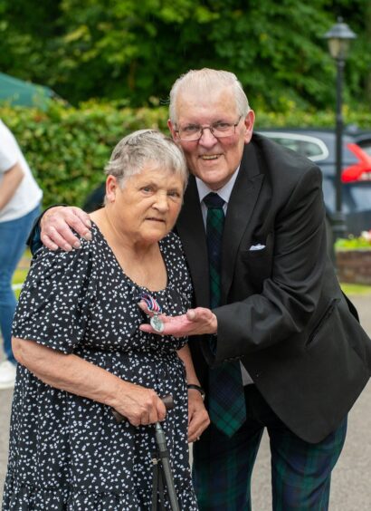 Christine and John Matheson standing side by side in the car park having their photograph taken.