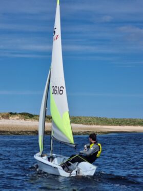 person sailing on blue water with sand and blue sky behind.