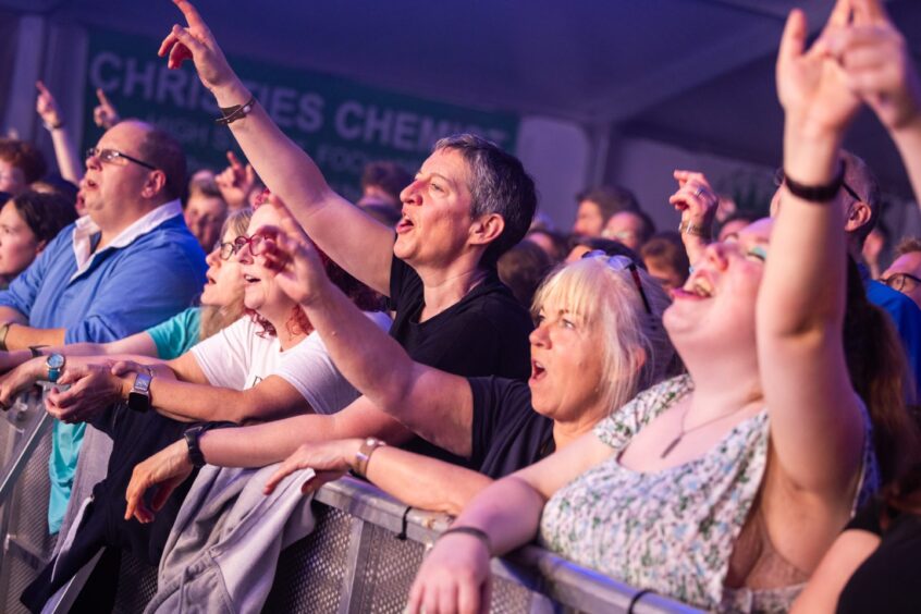 Crowds stretch out their arms at the front of the crowd barriers as they enjoy Speyfest.