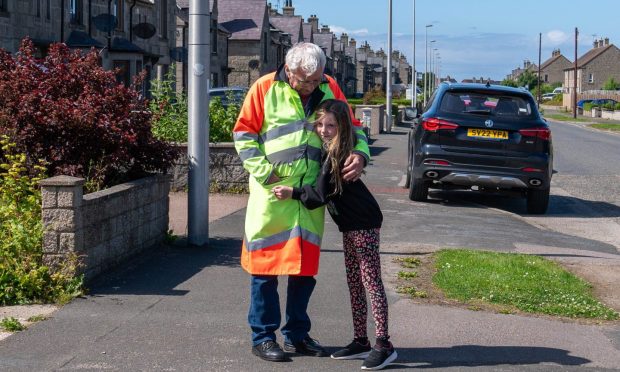 One last hug: Evie Simpson (nine) says goodbye to David Downie in Fraserburgh as Aberdeenshire lollipop people are removed from schools.
