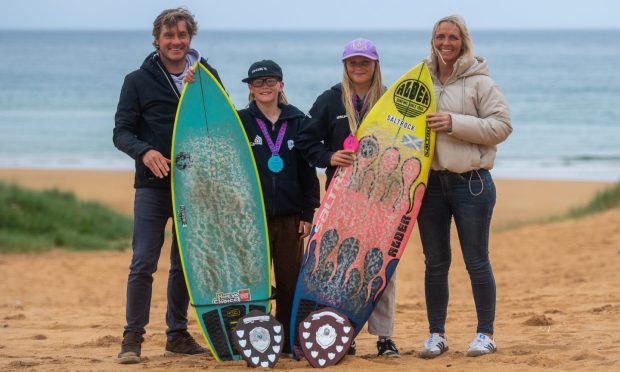 Cruickshank family on beach posing with surfboards
