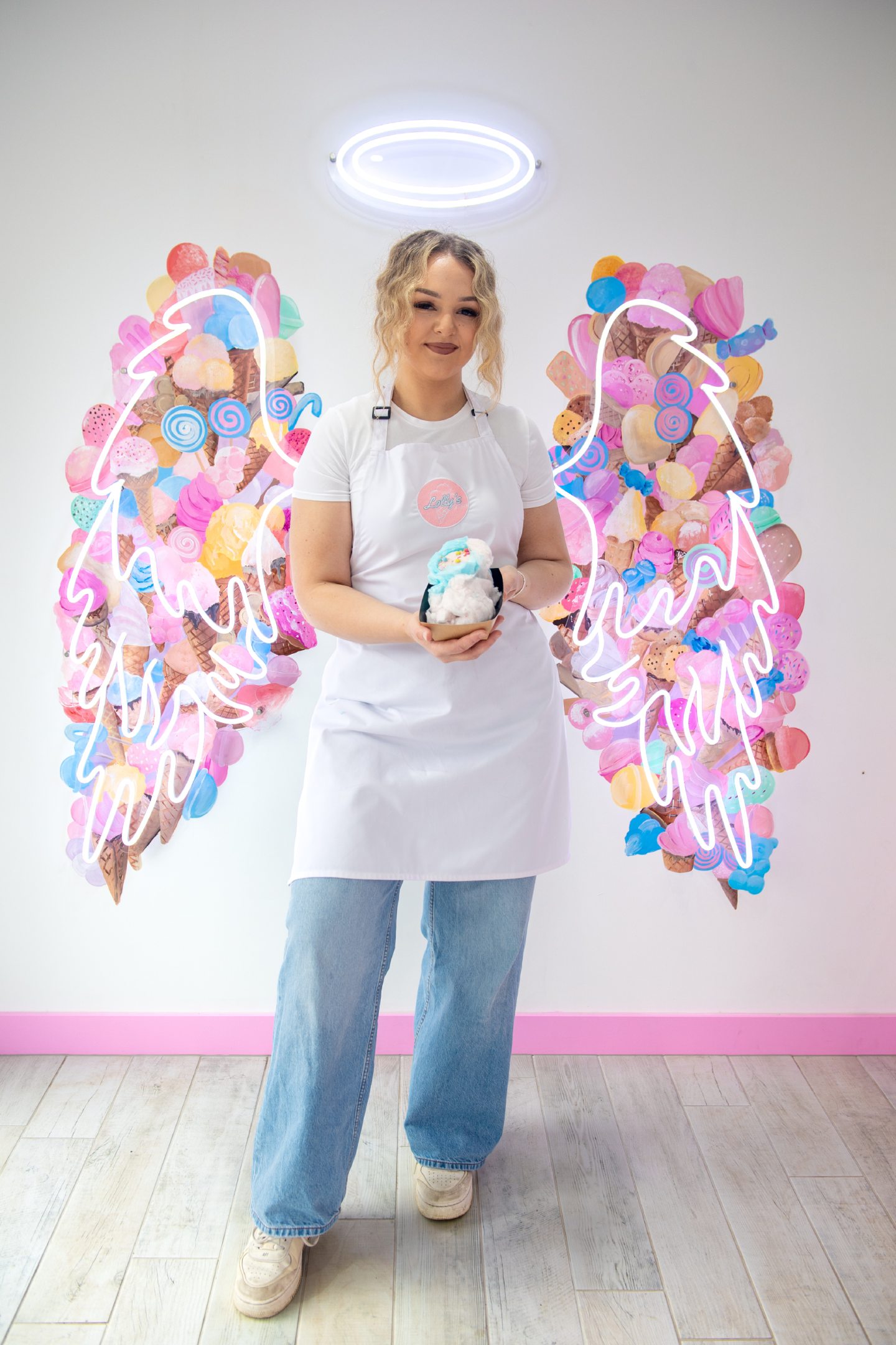 Lauren standing in front of the neon angel wings in her shop