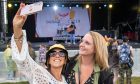 Two women taking a selfie in front of a festival stage