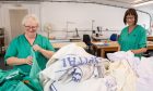 Maureen and Angela tackle a load of laundry brought to the sewing room. Image: Kami Thomson/DC Thomson
