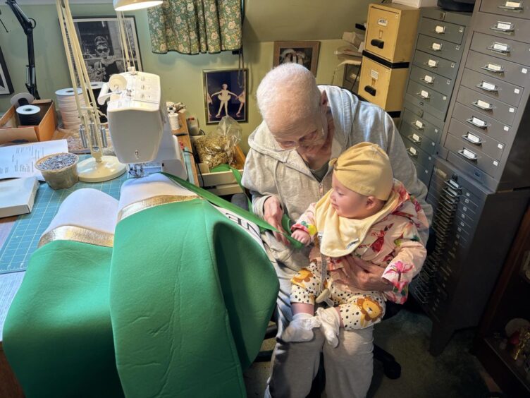 Liz showing her granddaughter Grace her sewing.