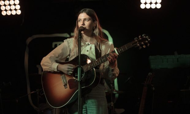 Rosie H Sullivan on stage with a guitar