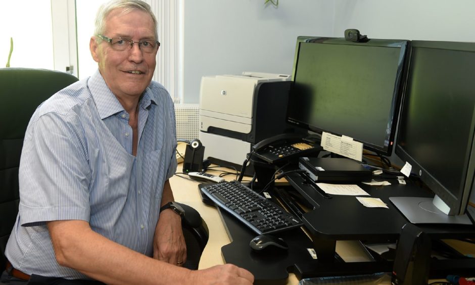 Dr Ron Stewart in consulting room at desk. 