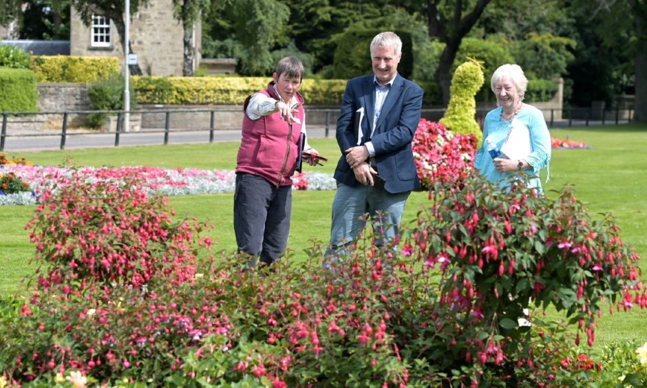 Britain in Bloom judges Geraldine King and Nick Jones pointing at flower display in Grant Park.