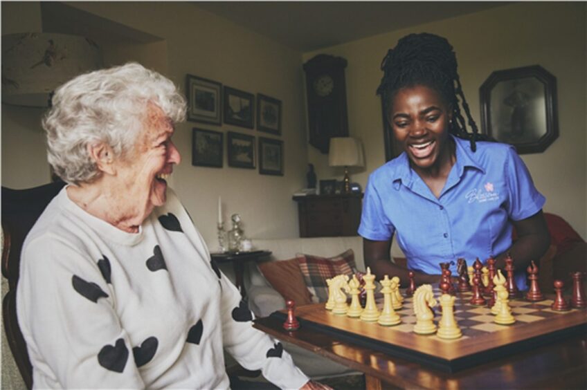 a blossom home care carer plays chess with a service user