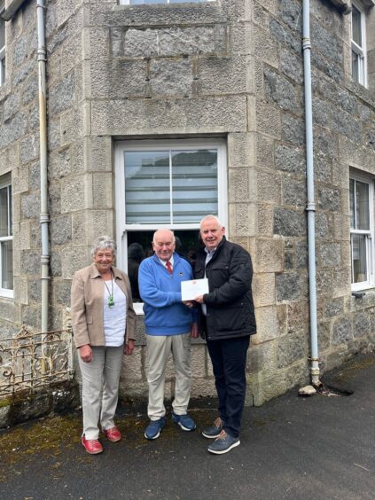 Pictured is Marjorie and Alisdair Mackenzie with Post Office Regional Manager, Kenny Lamont outside the original site of the local Post Office. 