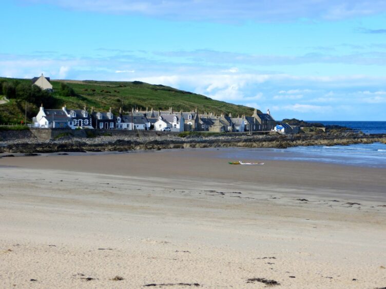 The beach in the foreground with the homes of Sandend village in the distance