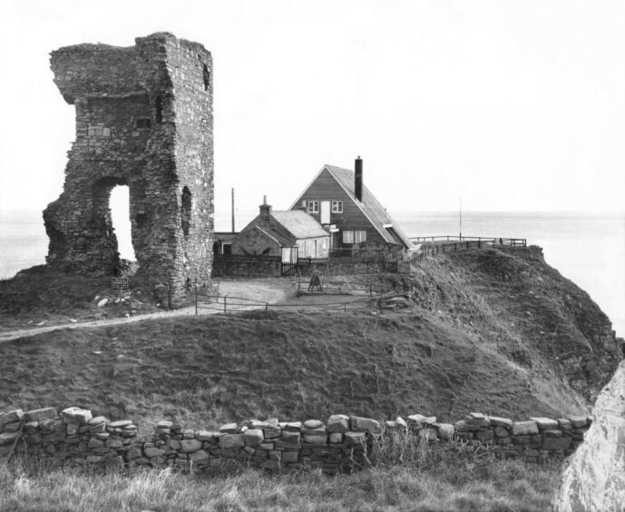 An image of Old Slains Castle from October 1973, with a home featured in the background