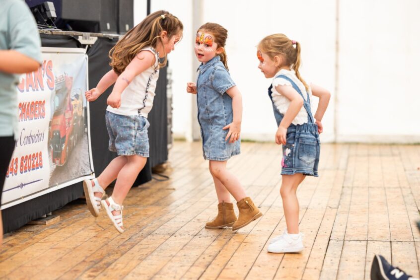 Three children jumping about a hall.