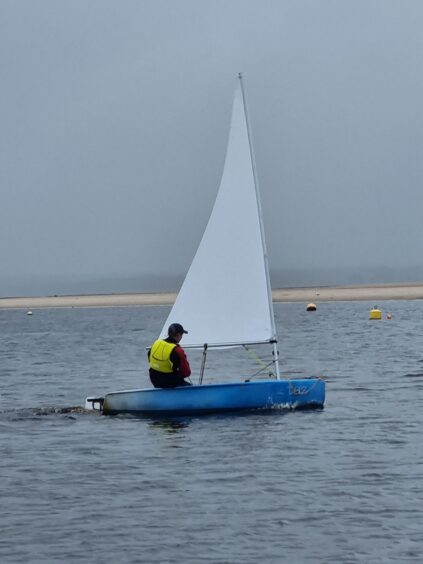 person sailing on blue water with a backdrop of grey sky 