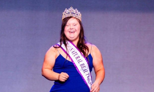 Taylor Clark pictured in a dark blue dress wearing a sash.