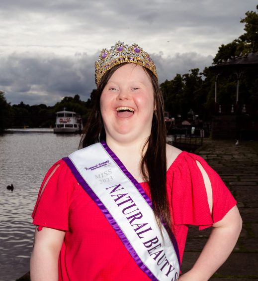 Beaming Taylor Clark pictured at the Queen's tea in a pink dress wearing a white and purple sash.