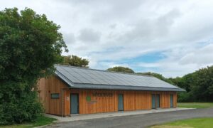 Facilities block with wooden panels and solar panels on the roof.
