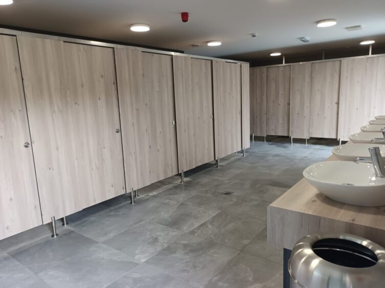 Toilet block with marble flooring and light wood finishes