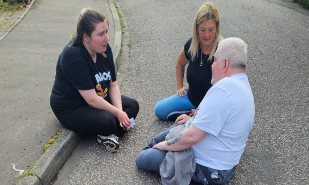 Eddie Terry sitting on the road with two women.