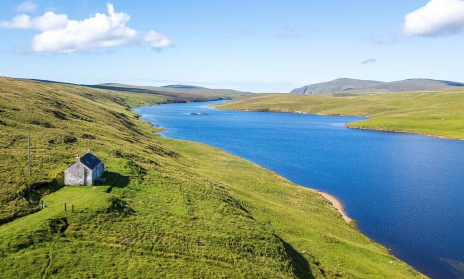 Beautiful cottage on Unst in Shetland, sitting near water amid green fields