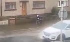 A man is sitting in a camping chair as cars battle through floods in the Blue Toon. Image: Peterhead Live.