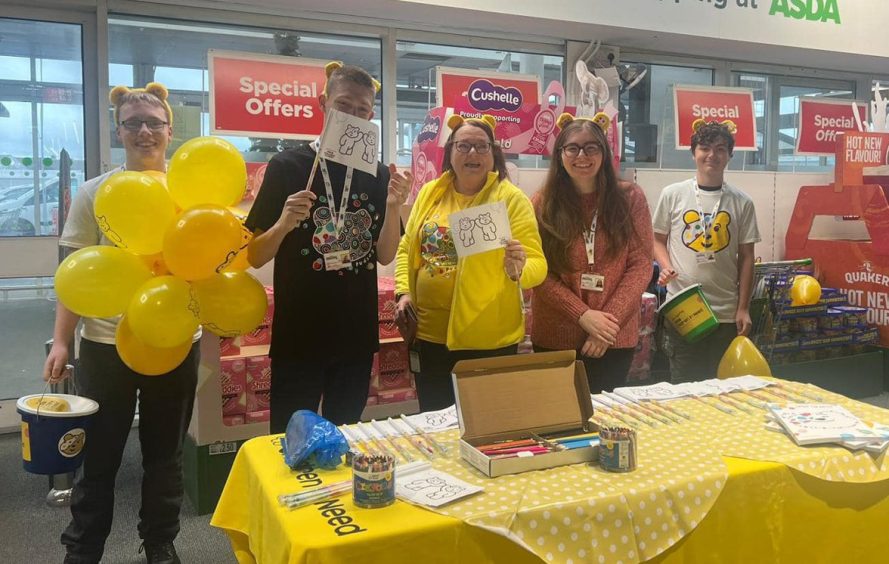 Riley with other volunteers behind a stall in Asda for children in need.