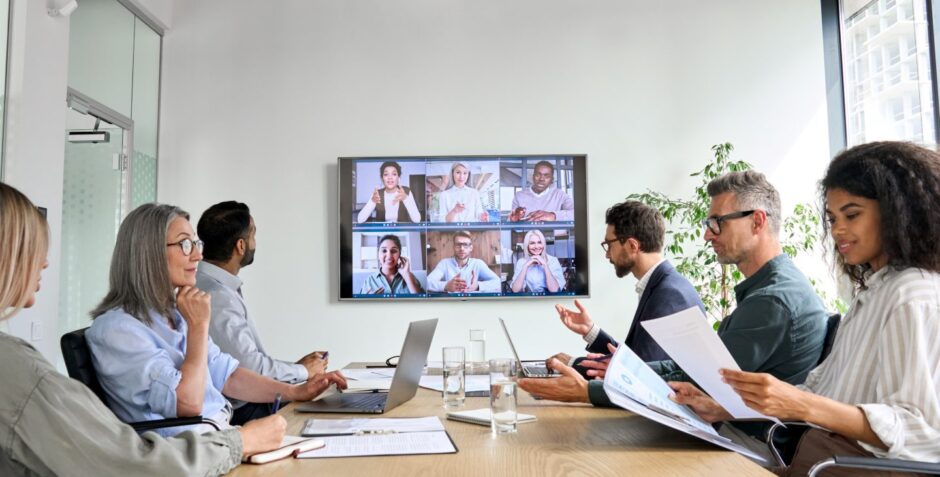 Diverse company employees having online business conference video call on tv screen monitor in boardroom. 