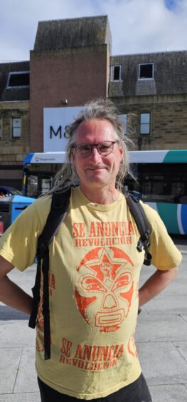 Marcus dressed in a yellow t-shirt with black backpack and glasses.