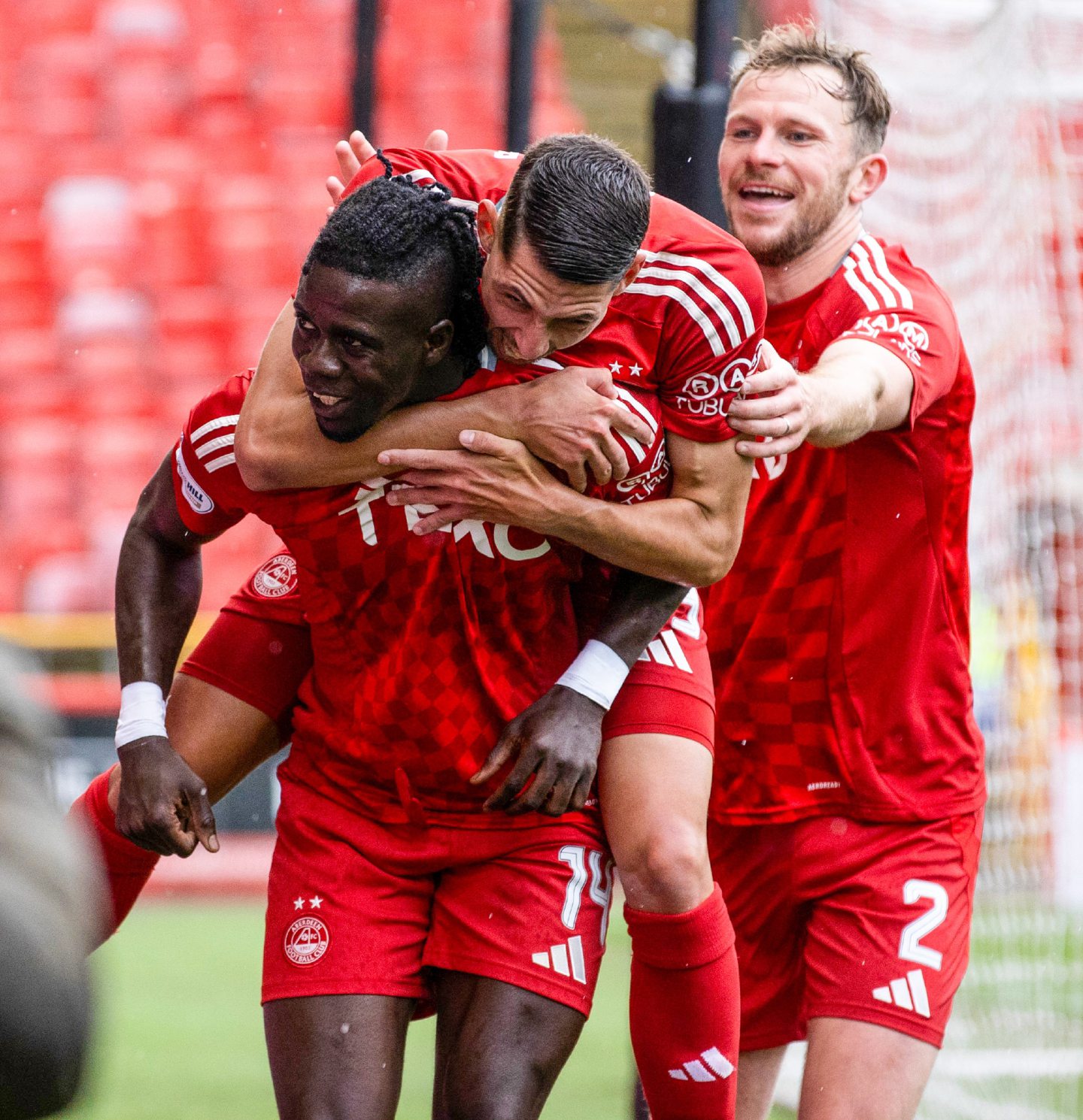 Aberdeen's Pape Habib Gueye (L) celebrates scoring to make it 1-0 with Ester Sokler and Nicky Devlin against Kilmarnock. Image: SNS