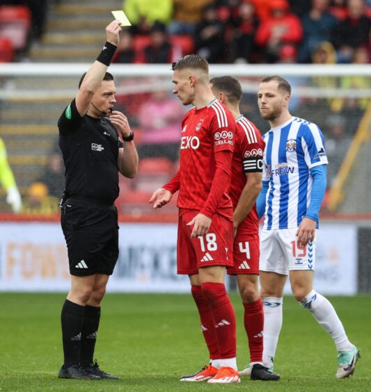 Aberdeen's Ante Palaversa is shown a yellow card by referee Matthew MacDermid against Kilmarnock. Image: SNS.