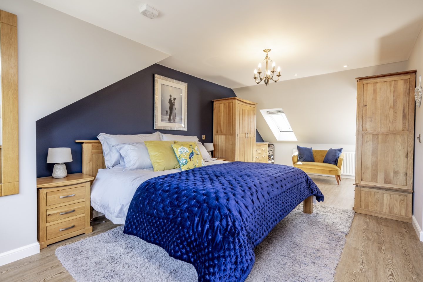 The master bedroom in the converted loft, there is a navy accent wall to match the blue and yellow furnishings