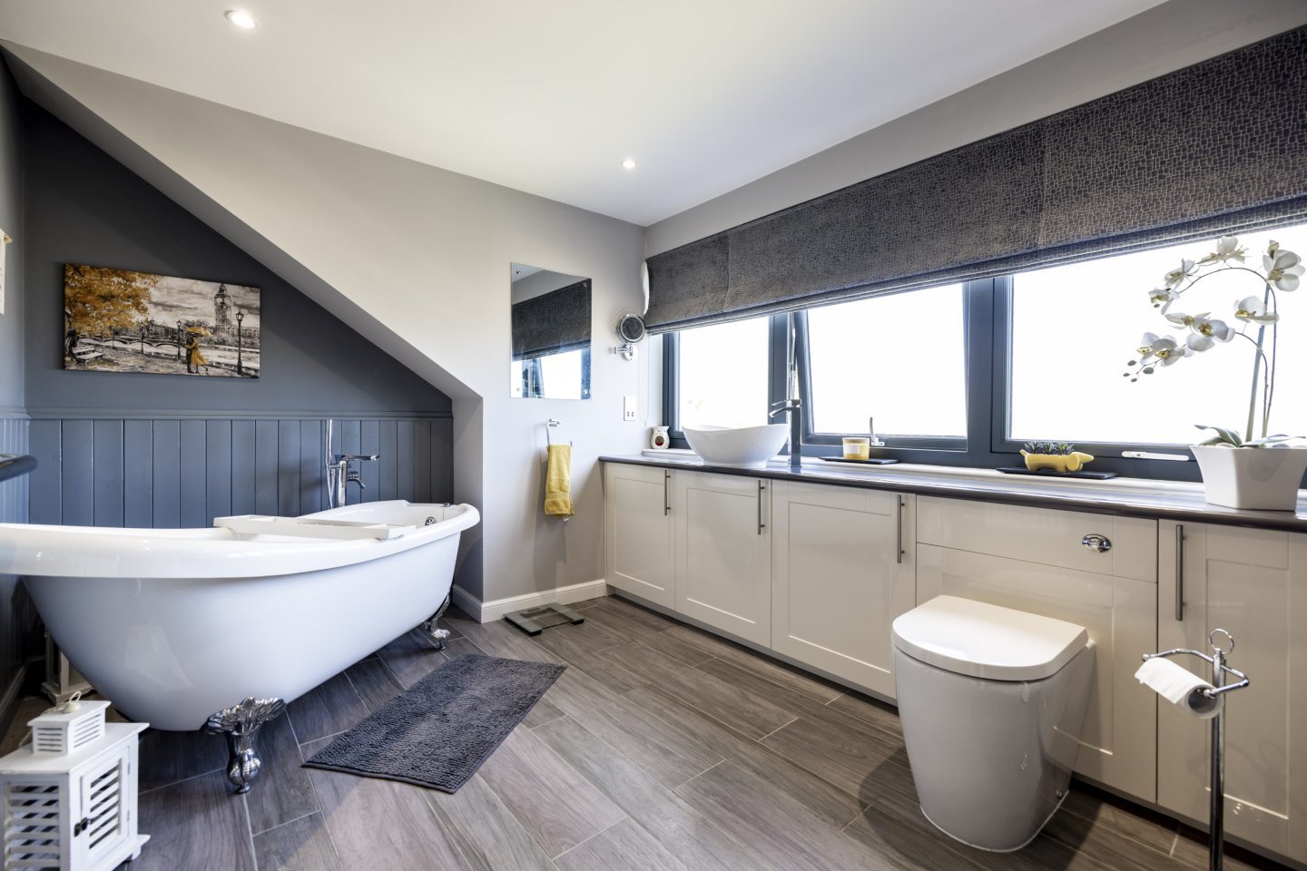 The grey and white en-suite bathroom in the west end apartment in aberdeen, including a freestanding bathtub and lots of natural light