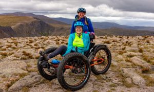 Karen Cox with one of her support team at the top on Cairngorm. The disabled adventurer cycled up the mountain on a recumbent eBike. Image: Supplied by Outfit Moray