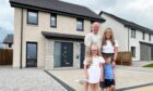 Sutherland family stands in front of their home, one of many houses in Aberdeenshire