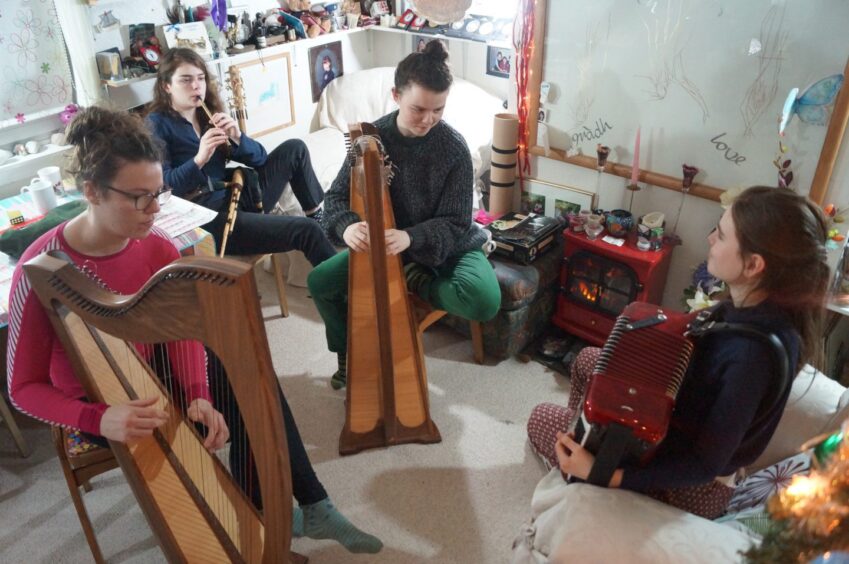 The four daughters of Angus Peter and Lionsaidh Campbell playing various instruments in the living room. 