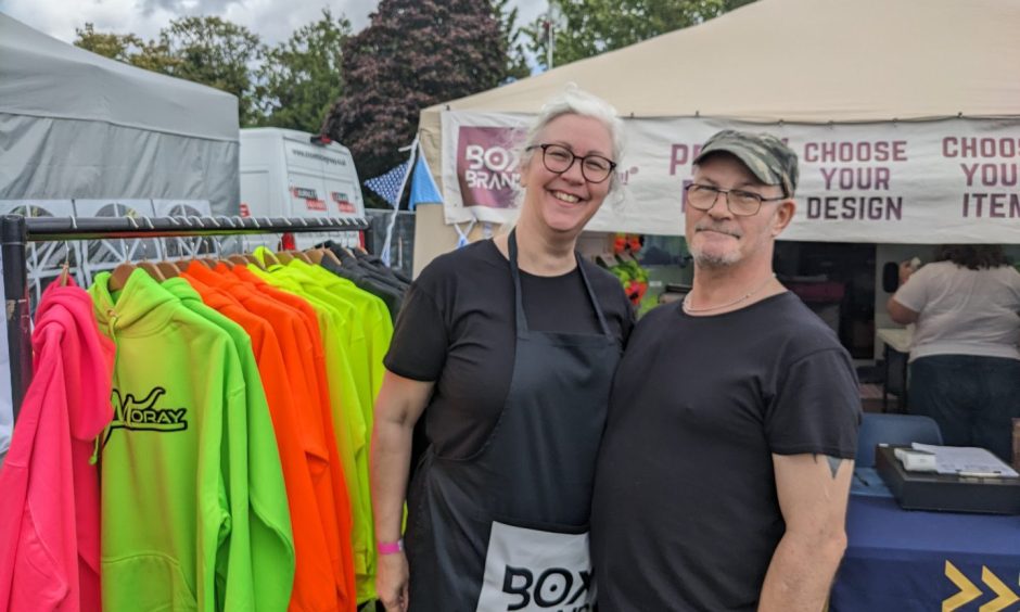 Lee and Grant Midlane next to row of MacMoray hoodies. 