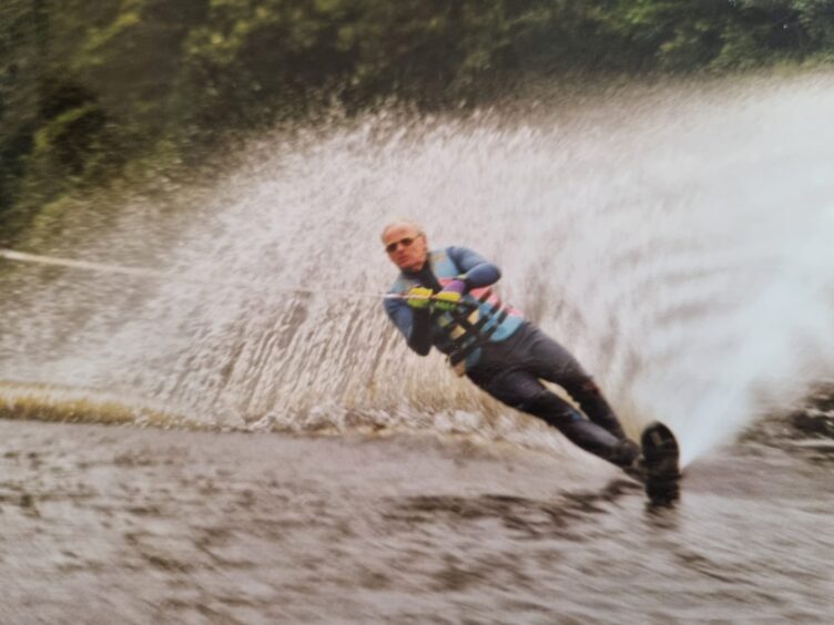 James Campbell waterski-ing on the river Beauly with a plume of water behind him.