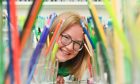 Sarah Holmes smiling at camera through tunnel of pencils.