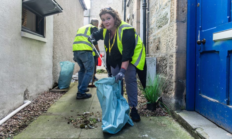 Jenny Urquhart putting rubbish in bag. 