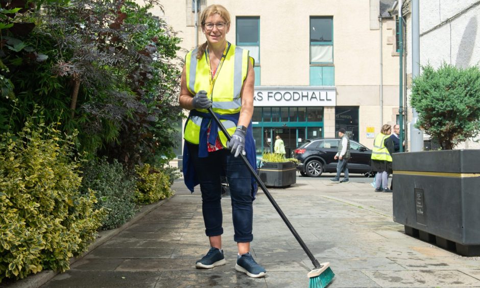 Kathleen Robertson holding broom on Elgin High Street. 