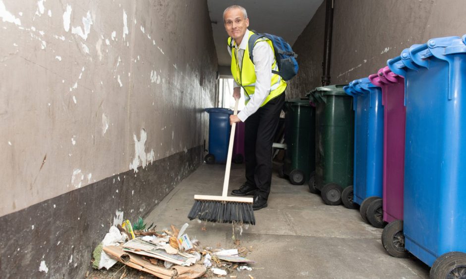 Sandy Keith sweeping rubbish in alleyway. 