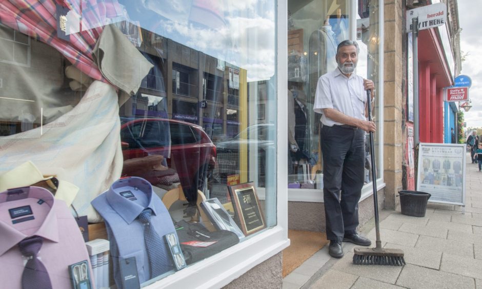 Nasir Mahmud with broom outside Emporium Menswear. 