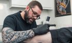 Mike Farquhar tattooing a leg.