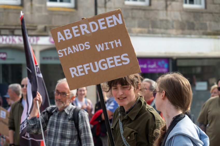 Anti-racism campaigner holds 'Aberdeen stands with refugees' sign at Castlegate peaceful protest.