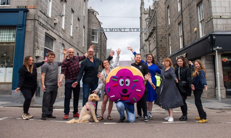 Belmont Street traders, who are taking part of the Yoga Big Belmont Bash, posing with jazz hands in the air.