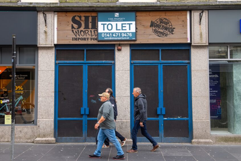 People walk past the front of 57-59 Union Street, Aberdeen, a vacant unit with a To Let sign out front.