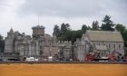 The exterior of Dunecht House. There are vehicles and some scaffolding that make it look like there is a film crew in the premises.