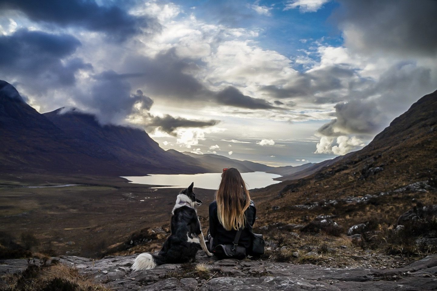 Luna the scottish collie and her owner Tsara facing away from the camera while hillwalking in the highlands